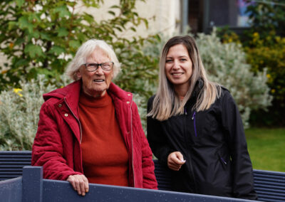 An older woman (Margaret) and her Support Practitioner standing in a garden. Carr Gomm