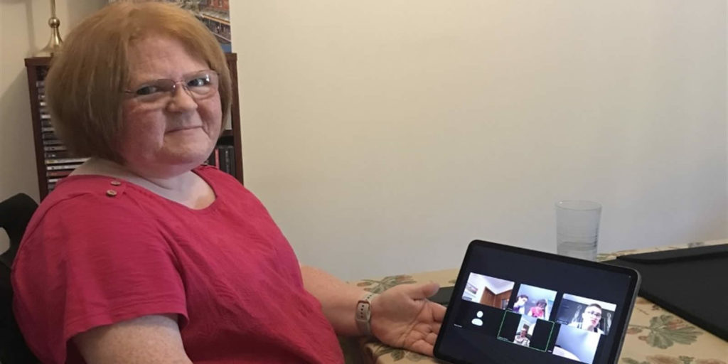 A woman (Anne) sitting at a desk with an iPad
