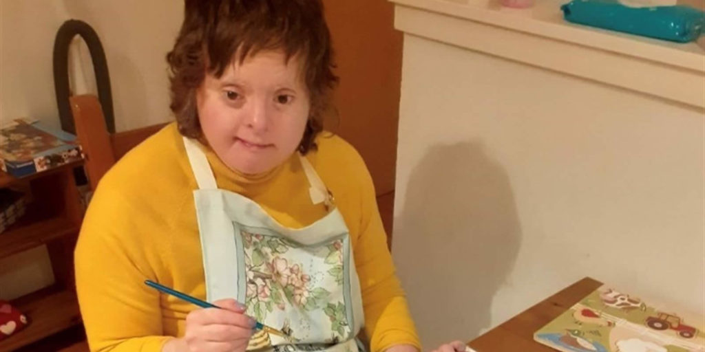 A woman (Gaynor) wearing an apron and holding a paint brush. 