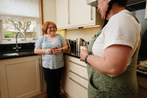Carr Gomm - Stirling & Falkirk<br /> Picture by Stewart Attwood<br /> All images © Stewart Attwood Photography 2021. All other rights are reserved. Use in any other context is expressly prohibited without prior permission. No Syndication Permitted. Fee for Use Two women are standing in the kitchen holding coffee mugs. They are smiling at each other.
