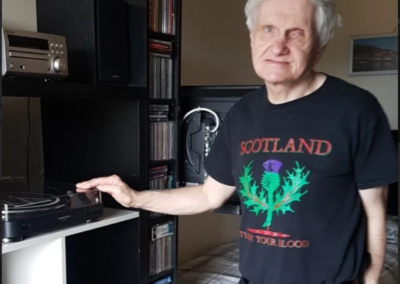 A man (James) stands next to his record player