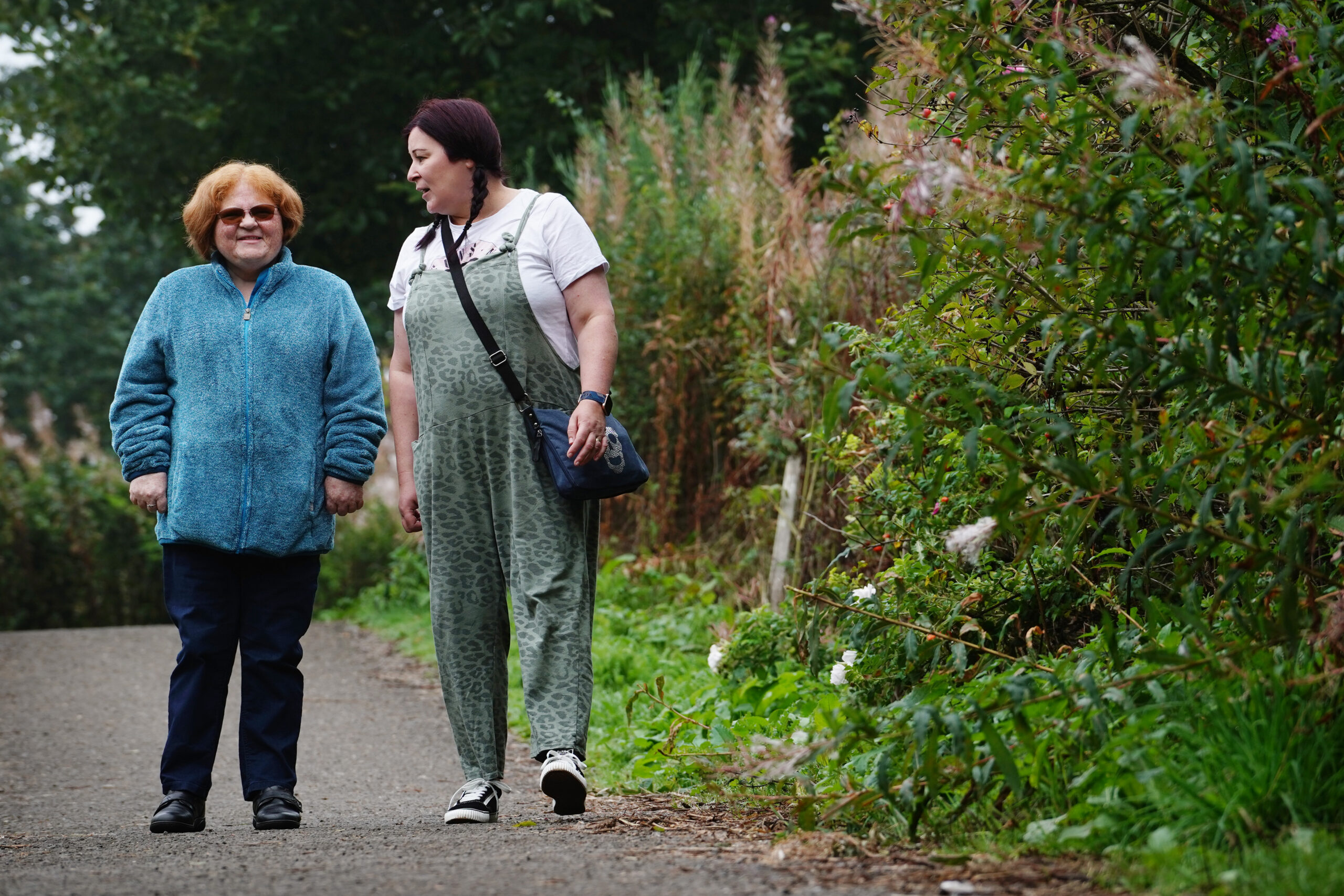 Woman walking in the park and smiling with her Personal Assistant.