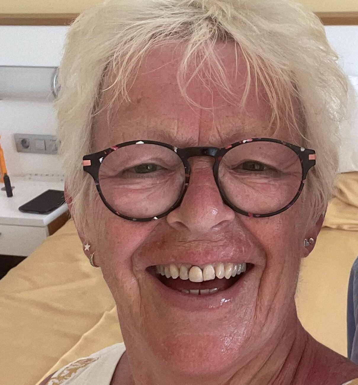 woman with glasses and grey hair smiling.