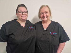 Tiffany and Alison (Support Practitioner Dunoon & Cowal) standing against a neutral background in black tunics. | Carr Gomm