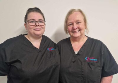 Tiffany and Alison (Support Practitioner Dunoon & Cowal) standing against a neutral background in black tunics. Carr Gomm