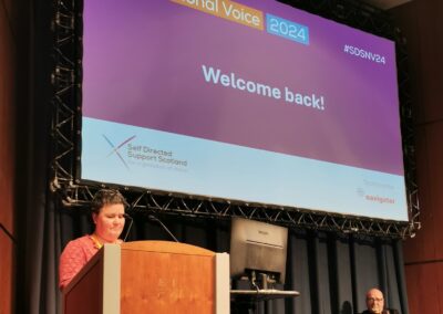 Woman standing behind lectern in front of screen which reads 'SDS National Voice 2024 Welcome back!'