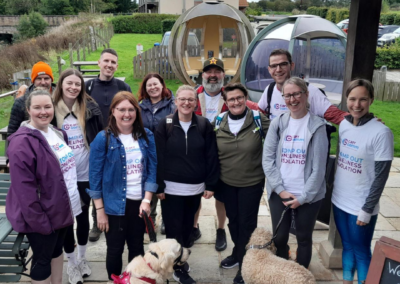 A group photo of twelve people and two dogs who are smiling outside a restaurant