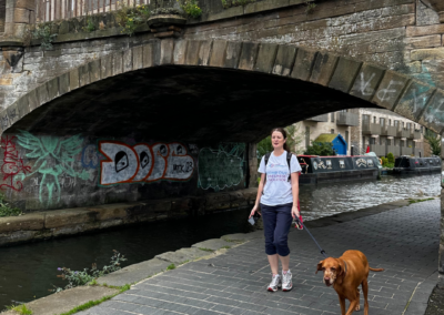 A woman walks her dog alongside a canal