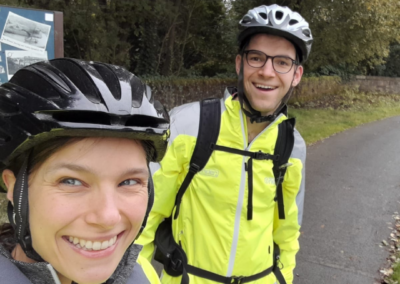A selfie of a man and a woman (Euan and Beth) with cycling jackets and helmets on