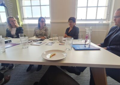 Three women and one man sit at a table deep in conversation.