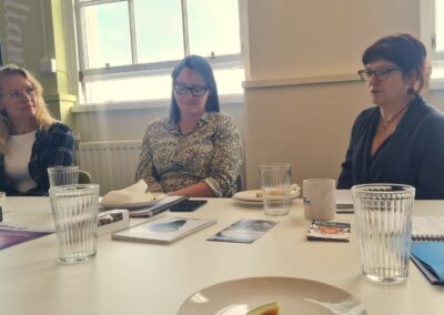 Three white women sit at a table talking.