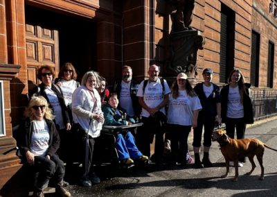 A group photo of eleven people and a dog standing outside of the Carr Gomm office in Fairfield, Glasgow