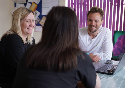 Two women and a man sitting at a desk and chatting. Carr Gomm