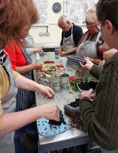 Craigmillar Community Grows: A group of people are standing round an industrial kitchen counter washing and preparing berries.