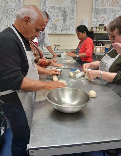Craigmillar Community Grows: Four people stand at an industrial kitchen counter, each rolling out dough.