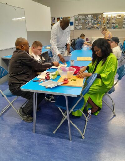 Craigmillar Community Grows: A group of people sit at a blue table, cutting vegetables and fruit.
