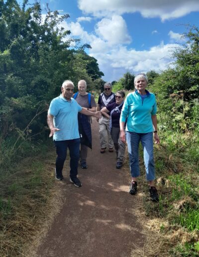 Craigmillar Community Grows: A grow of older individuals walk along a woodland path, smiling.