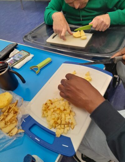 Craigmillar Community Grows: Two people are cutting vegetables on white cutting boards.