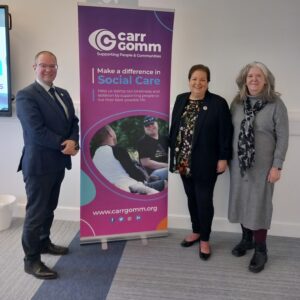 Jackie Baillie, Lucy Wren and Andrew Thomson smile for the camera next to a Carr Gomm banner.