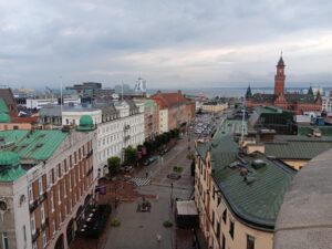 Sweden Peer Learning Visit: A view of a Swedish street from a high floor. Water and a tall church steeple are visible in the distance. 