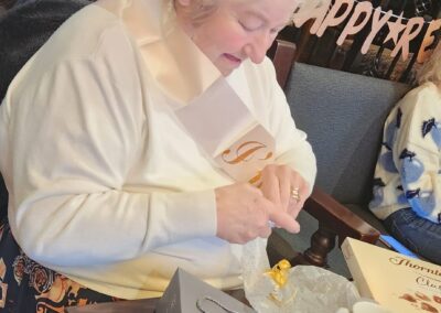 A woman (Maureen) opening a gift at a table decorated with a 'Happy Retirement' sign, with a coffee cup and other wrapped gifts nearby | Maureen’s retirement celebration after over two decades of working in the social care sector.