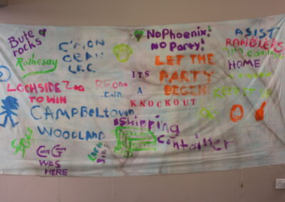 A sheet is hung on the wall painted with names and sayings.