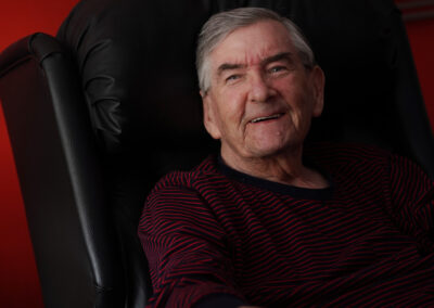 An older man sitting in a comfortable arm chair and smiling
