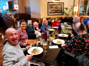A group of people are in a restaurant. They are smiling at the camera.