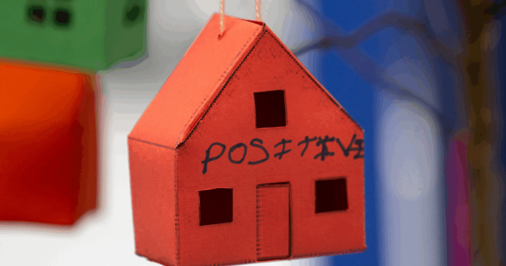 Paper house hanging from strings with the word postitive written on them. | Housing Support in Argyll and Bute