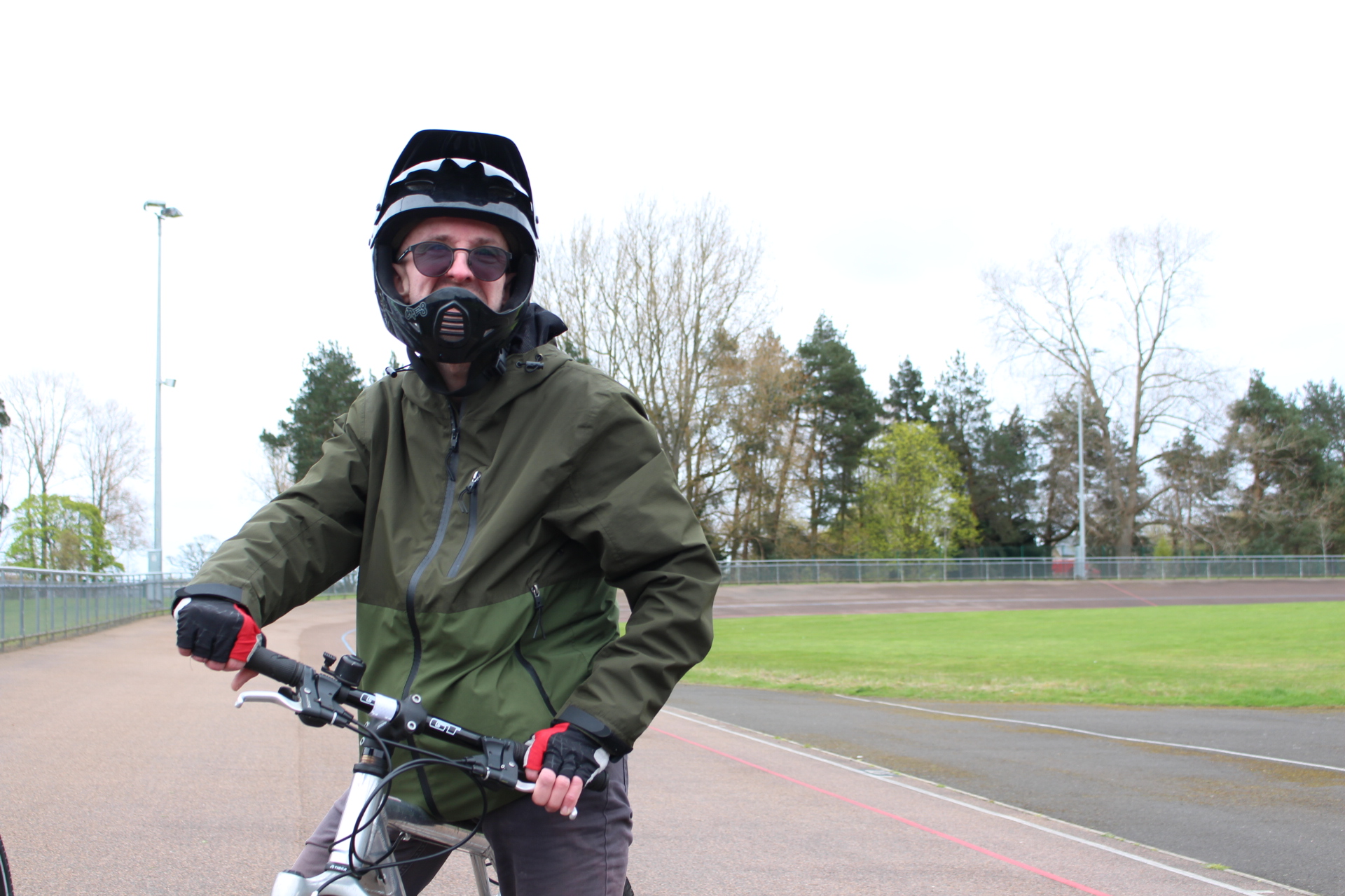 Person with full face bike helmet ready to ride. On a concrete track with trees in the background