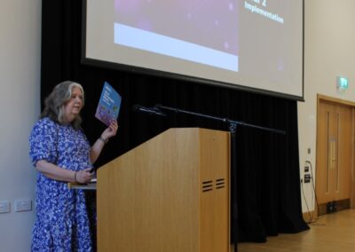 Person holds a copy of the Carr Gomm Strategic Plan while standing behind a lectern.