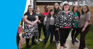 Group of people standing together in a backyard, smiling.