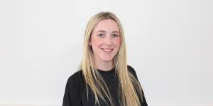 Person stands against white background smiling
