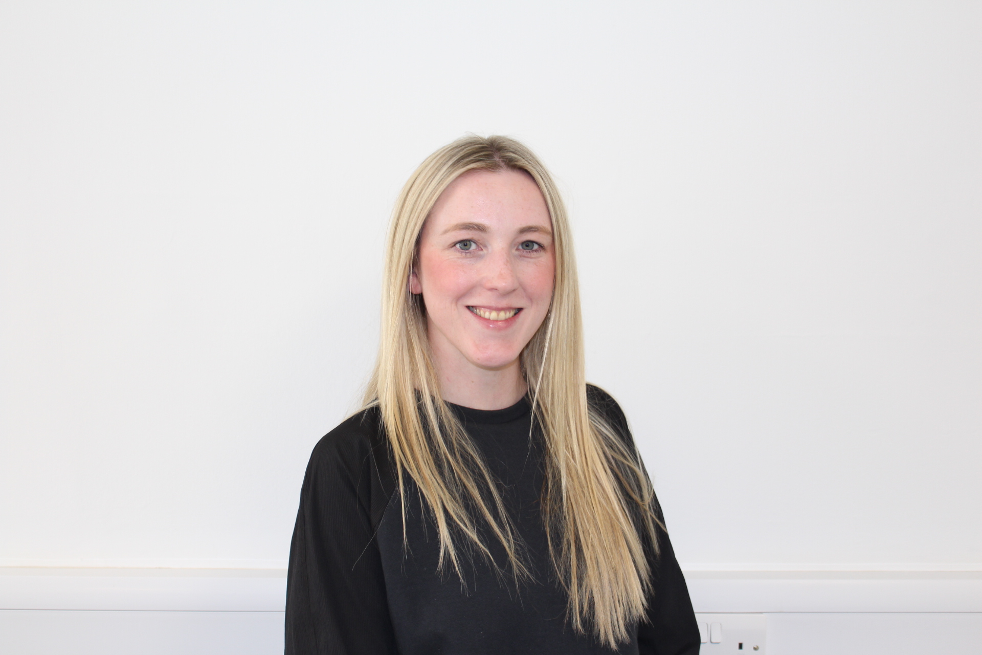 Person standing against white background smiling