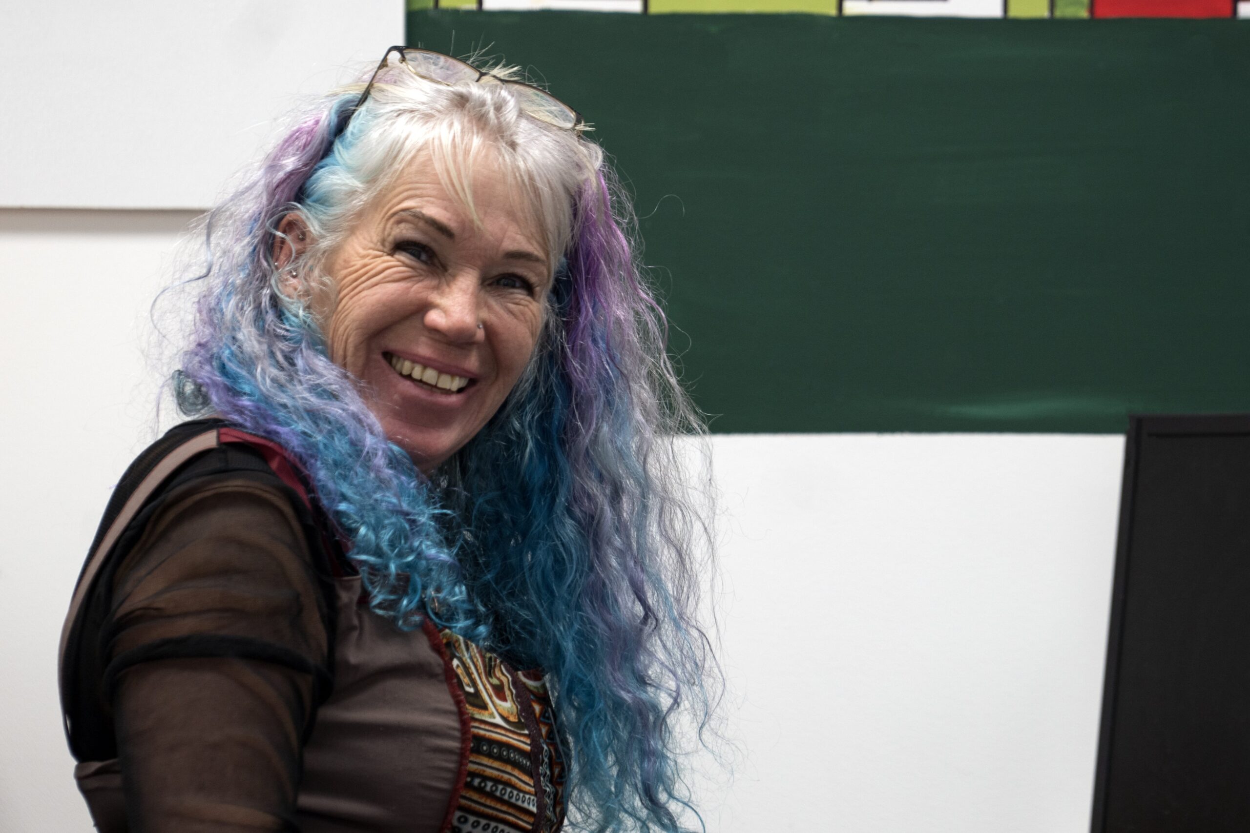 Person with colorful hair smiling in an office environment