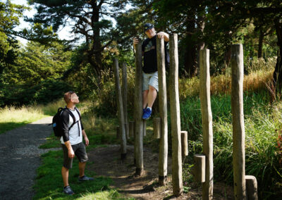 two men in an outdoor setting, one is standing on the groud the other stands on outdoor activity
