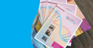 A glass bowl filled with wrapped chocolates sits on a colorful wooden table next to several copies of "Our Connections" magazine by Carr Comm.