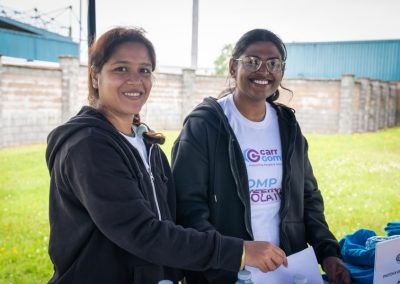 Two women in Carr Gomm shirts and black hoodies smile at the camera.