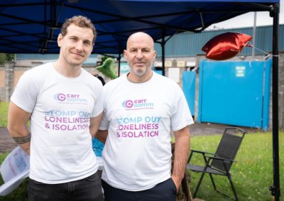 Two men in Carr gomm shirts smile for the camera