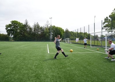 A man kicks a football towards the goal.