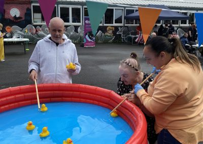 Carr Gomm Glasgow Forum - Three people are playing hook a duck in a small blow up swimming pool.