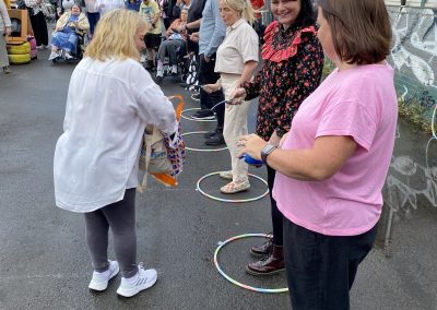 Carr Gomm Glasgow Forum - A line of people standing outside holding spoons. One women is handing them eggs from a plastic bag.