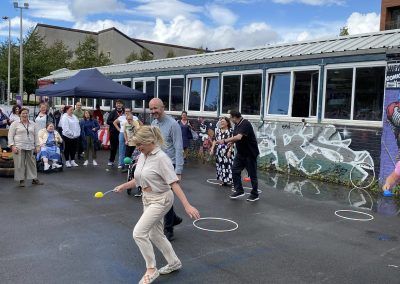 Carr Gomm Glasgow Forum - A group of people competing in an egg and spoon race, next to a building with colourful graffiti.