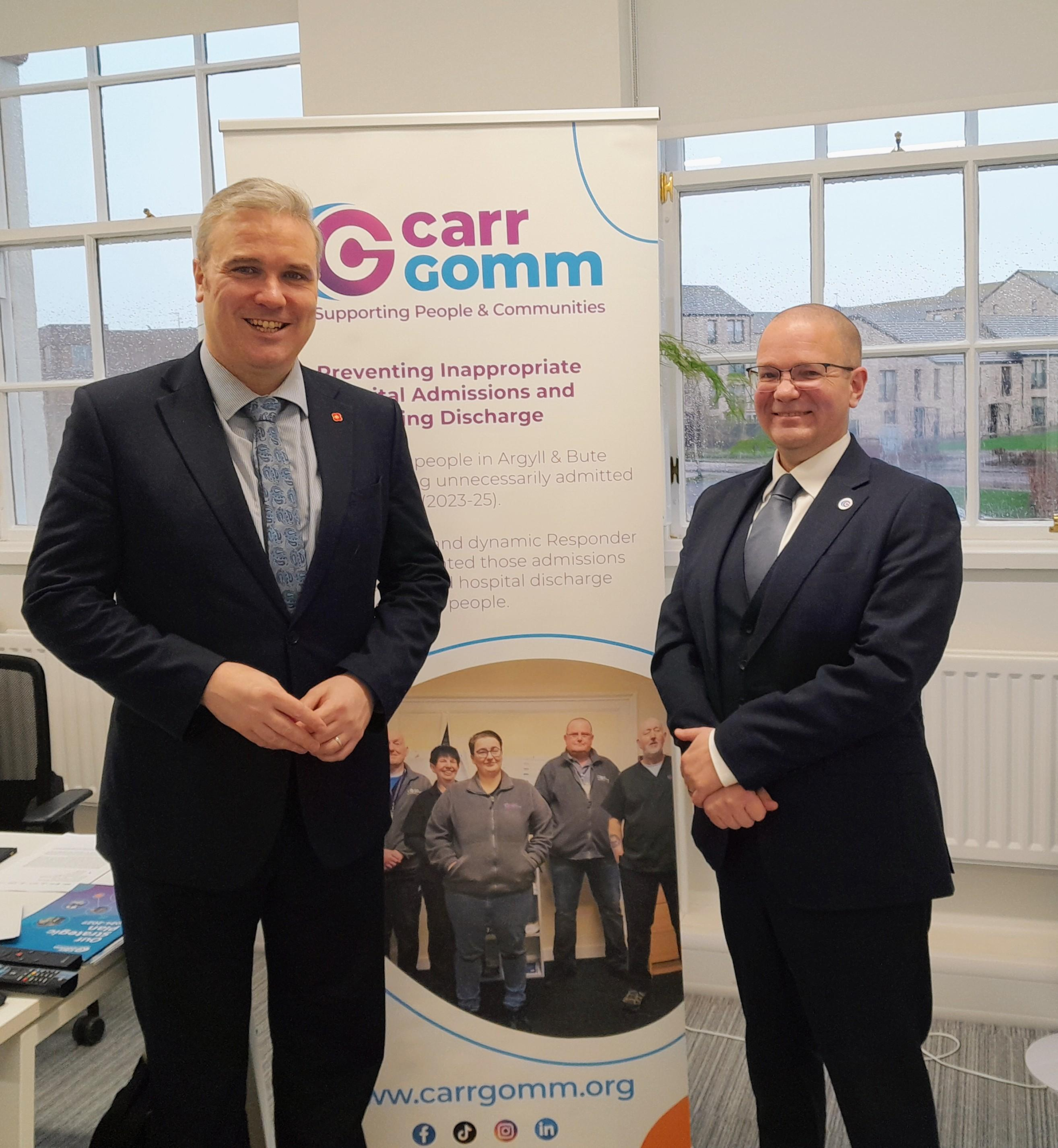 Two men in suits stood in front of Carr Gomm banner