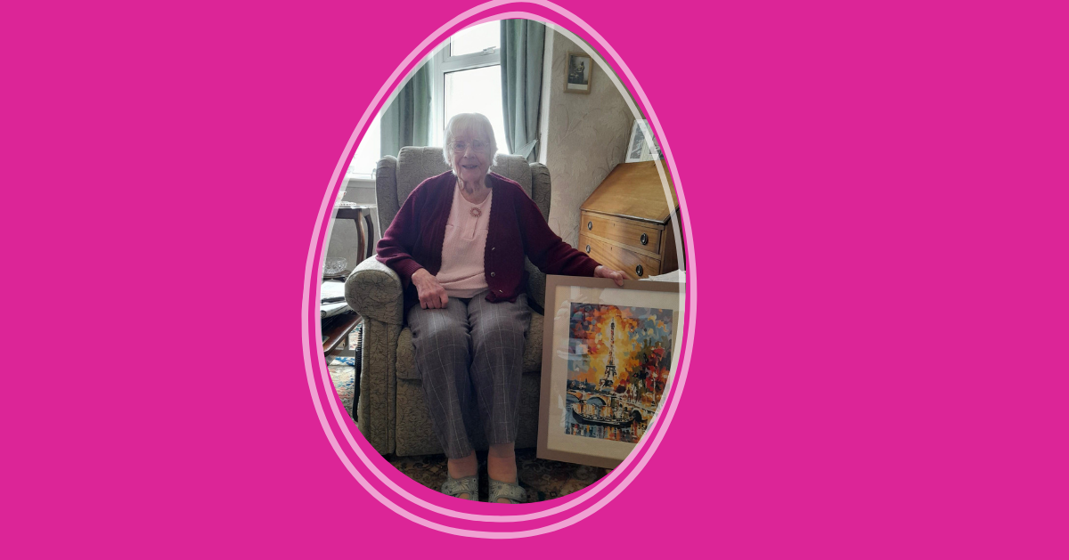 Katherine A woman seated on an armchair in a living room showing a painting of sunflowers.