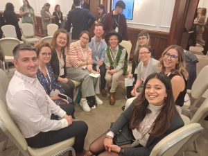 A group of people sitting in a circle, all looking at the camera and smiling.
