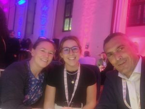Two women and a man smile at the camera. They are in a party telling with blue and pink lights on the wall behind them. EASPD Conference in Turin