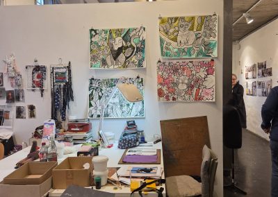 An art studio space with several cat paintings can be seen on the wall.