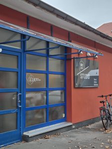 Exterior of Un-label studio space, with red walls and blue doors.