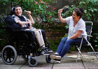 A man in a wheelchair and a woman in a lawn chair playing percussion instruments